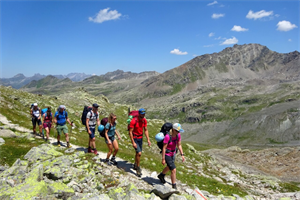 6 Personen wandern bei strahlendem Wetter durch das Gebirge