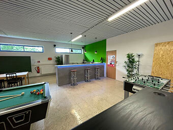 ein Raum mit Billardtischen und grünen Wänden