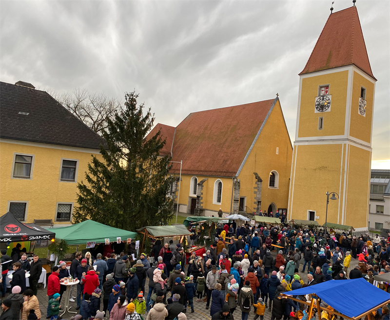 Adventmarkt am Feldkirchner Marktplatz - viele Menschen vor Ständen und der Kirche